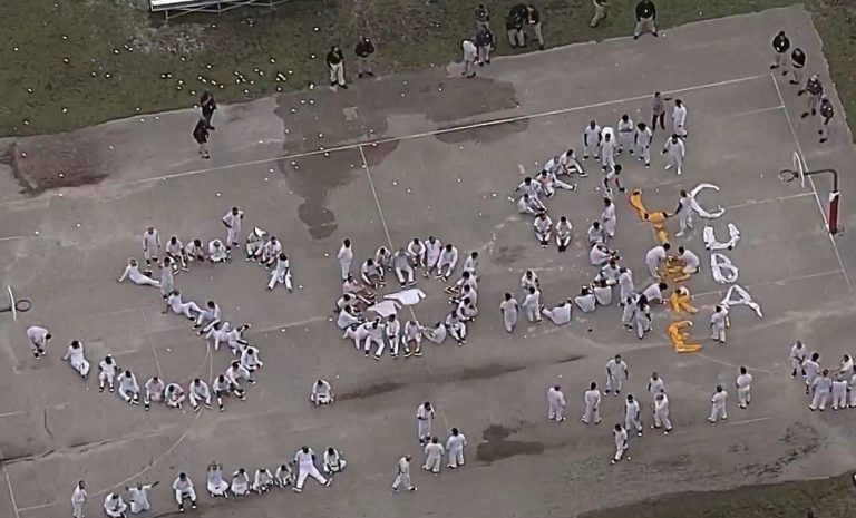 Migrantes forman las palabras “SOS Cuba” en Centro de Detención de Krome